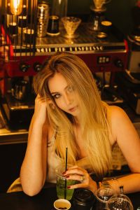 Image of a beautiful blonde woman sitting at a bar with a drink in her hand