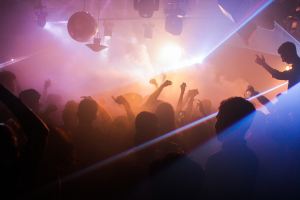 Image of people dancing in a club with dim lights, smoke, lasers, and disco ball.